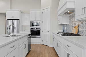 Kitchen with white cabinetry, light stone counters, light wood-style flooring, and stainless steel appliances