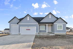 View of front facade featuring a garage, covered porch, concrete driveway, board and batten siding, and roof with shingles