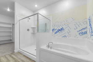 Bathroom featuring a stall shower, a bath, light wood finished floors, and a spacious closet