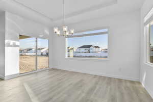 Unfurnished dining area with plenty of natural light, a chandelier, and light wood-type flooring