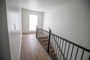 Corridor featuring light wood-style flooring, a textured ceiling, and an upstairs landing