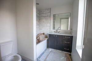 Bathroom with vanity, a tub, and concrete flooring