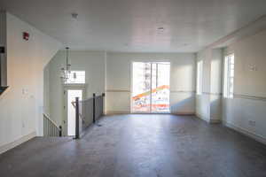 Unfurnished living room featuring hardwood / wood-style flooring, a textured ceiling, and a chandelier