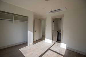 Unfurnished bedroom with wood finished floors and a closet