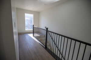 Corridor featuring an upstairs landing, dark wood-style floors, and a textured ceiling