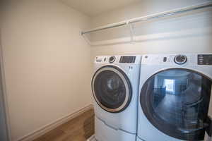 Laundry area with wood finished floors and washing machine and dryer