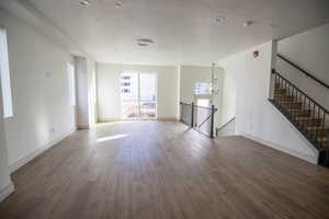 Unfurnished living room with hanging lights, a textured ceiling, and wood finished floors