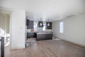Kitchen featuring dark brown cabinets, a kitchen island with sink, dark wood-type flooring, open floor plan, and custom exhaust hood