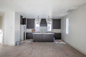 Kitchen featuring dark brown cabinets, a kitchen island, hanging light fixtures, and dark wood-style flooring