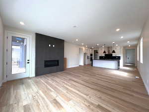 Living room with healthy amount of natural light, a large fireplace, light wood-style floors, and access to covered balcony.
