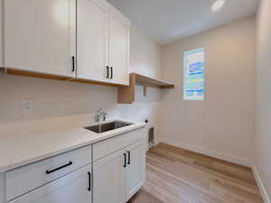 Laundry area with laundry sink, white cabinets, quartz countertops and electric dryer hookup