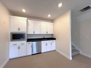 Basement kitchenette featuring white cabinetry, granite countertops and stainless steel appliances.