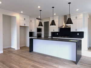 Kitchen featuring chef's kitchen, pendant lighting, white cabinetry, granite waterfall kitchen island and Kitchen Aid appliances.