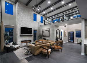 Living area with beam ceiling, dark wood finished floors, a fireplace, and a towering ceiling