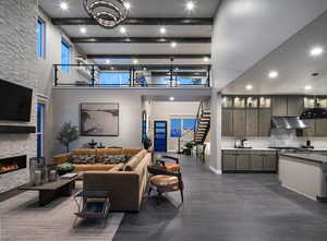 Living area featuring stairway, a stone fireplace, beam ceiling, a towering ceiling, and dark wood-style floors