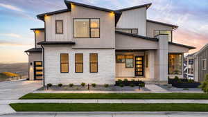 Modern home with stone siding, board and batten siding, stucco siding, and concrete driveway