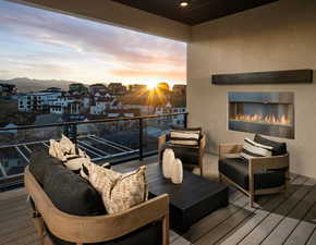 Balcony at dusk with an outdoor living space with a fireplace