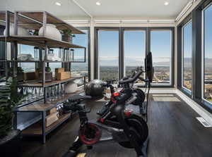 Exercise room with dark wood-style floors, recessed lighting, a wall of windows, and a mountain view