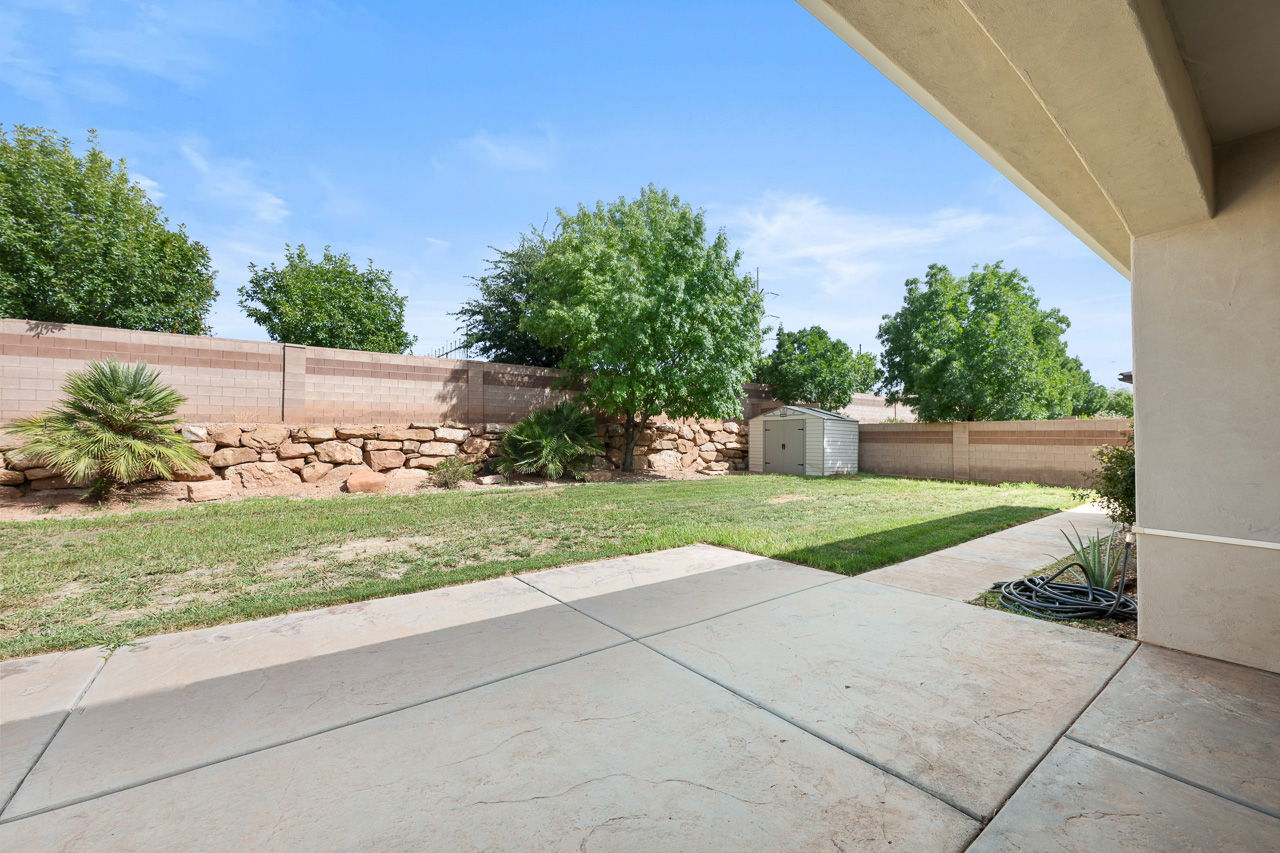 Fenced backyard featuring a patio and a storage unit