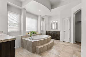 Bathroom featuring a closet, two vanities, a garden tub, recessed lighting, and light tile patterned floors