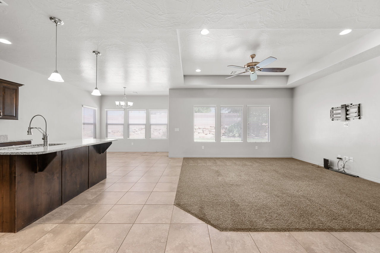 Kitchen with decorative light fixtures, a breakfast bar, dark brown cabinets, a ceiling fan, and a chandelier