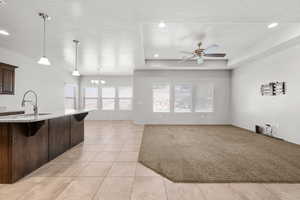 Kitchen with decorative light fixtures, a breakfast bar, dark brown cabinets, a ceiling fan, and a chandelier