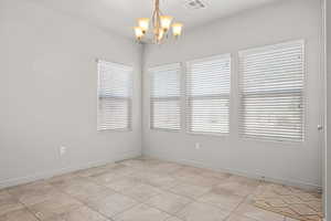 Spare room featuring a chandelier and light tile patterned floors