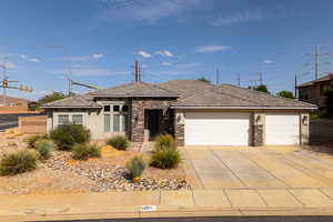 View of front facade with stone siding, a garage, stucco siding, and concrete driveway