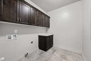 Washroom with cabinet space, a textured ceiling, washer hookup, and electric dryer hookup
