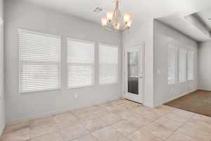 Unfurnished dining area featuring a chandelier and light tile patterned floors