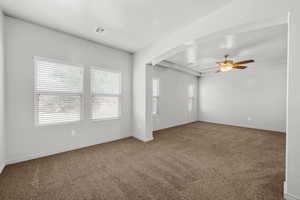 Carpeted spare room with arched walkways and ceiling fan