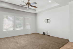Empty room featuring a tray ceiling, light carpet, recessed lighting, and a ceiling fan