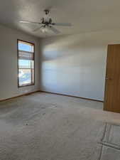 Carpeted empty room with a textured ceiling and a ceiling fan