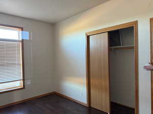 Unfurnished bedroom featuring a closet and dark wood finished floors
