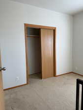 Unfurnished bedroom with a closet, light carpet, and a textured ceiling