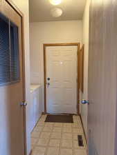 Laundry room with light floors, a textured ceiling, a heating unit, and separate washer and dryer