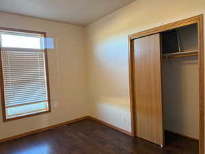 Unfurnished bedroom with a closet and dark wood-style floors