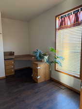 Unfurnished office featuring baseboards and dark wood-style floors