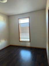 Spare room featuring dark wood-style floors and a textured ceiling