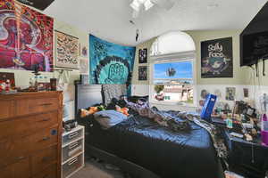 Bedroom with a textured ceiling, carpet, ceiling fan, and vaulted ceiling