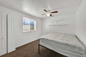 Bedroom featuring dark carpet, a textured ceiling, and a ceiling fan