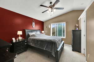 Bedroom with light colored carpet, a textured ceiling, lofted ceiling, and a ceiling fan