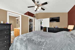 Bedroom with light tile patterned floors, vaulted ceiling, ceiling fan, ensuite bathroom, and a closet