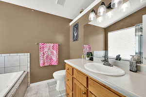 Bathroom with vanity, a garden tub, light tile patterned floors, and vaulted ceiling