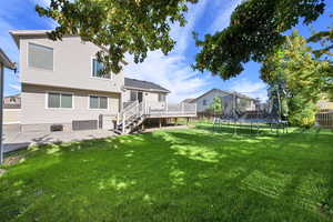 Fenced backyard with stairway, a trampoline, a deck, and a patio area