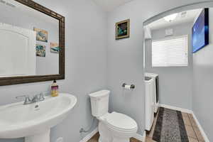 Half bath with washer and clothes dryer and tile patterned floors