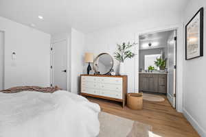 Bedroom with light wood-style floors, recessed lighting, and connected bathroom