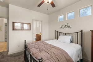 Carpeted bedroom with connected bathroom and a ceiling fan