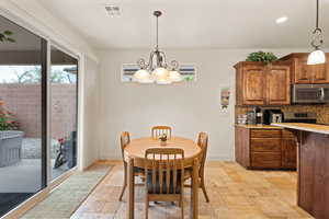 Dining area with stone tile flooring, recessed lighting, and a chandelier