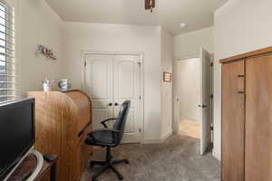 Carpeted home office with plenty of natural light and ceiling fan